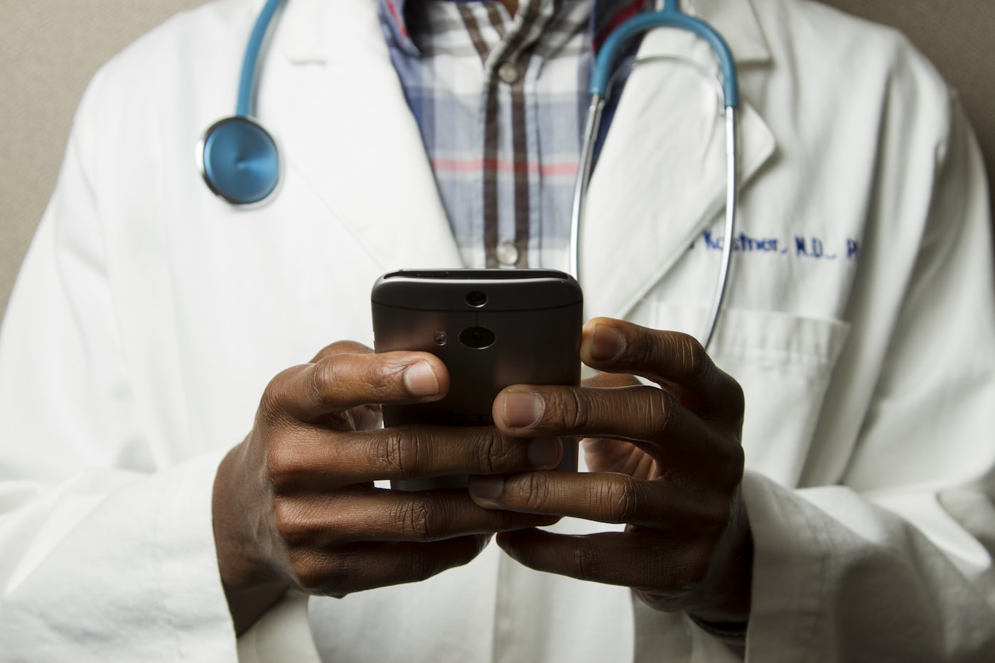 Medical student in a white coat using a phone with a stethoscope